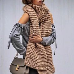 a woman is wearing a scarf and holding a purse