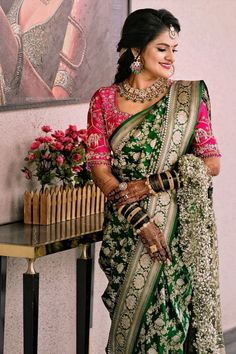 a woman in a green and pink sari standing next to a table with flowers