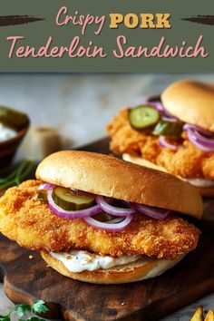 two chicken sandwiches with pickles and onions on a cutting board