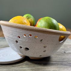 a white bowl filled with fruit on top of a wooden table