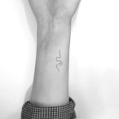 a person's arm with a snake tattoo on the left side of their wrist