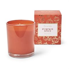 an orange candle sitting in front of a red box with pumpkin spice written on it