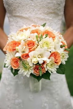 the bride's bouquet is made up of orange roses and white lilies, while she wears her wedding dress