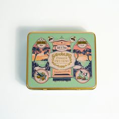 a small tin box with an image of trees and other things in it on a white surface