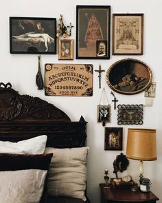 there is a bed with many pictures on the wall above it and a lamp next to it