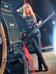 a woman standing next to a guitar on top of a stage