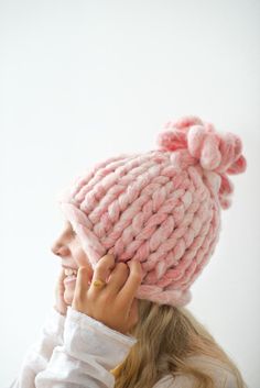 a woman wearing a pink knitted hat with pom - poms