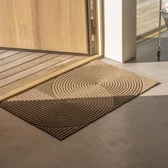 a door mat on the floor in front of a wooden door with a chair next to it