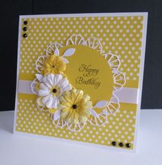 a yellow and white birthday card with flowers on the front, sitting on a table