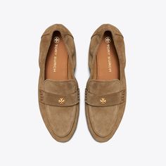 Our Ballet Loafer® is an interpretation of two classics — the flexibility of a ballet slipper with the profile of a loafer. The insole provides performance-level comfort, ruched sides secure the foot and treads on the outsole add traction. It is crafted in suede and detailed with a Double T in brushed gold. The shoe's edges are hand-painted and the strap is hand-stitched.  Crafted in partnership with a Leather Working Group-certified tannery, supporting high standards in leather manufacturing an Loafers Online, Designer Flats, Europe Trip, Ballet Slippers, Womens Aprons, River Rock, Tory Burch Flats, Suede Loafers, Footwear Design Women