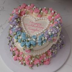 a heart shaped cake decorated with flowers and pearls