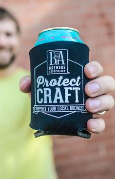 a man holding up a can of project craft beer