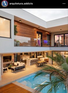 a house with a pool in front of it and a woman standing on the balcony