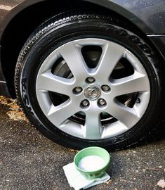 a cup is sitting on the ground next to a car's tire and wheel