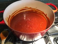 a pot filled with red sauce sitting on top of a stove