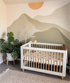 a baby's room with mountains painted on the wall and a white crib