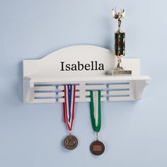 two medals are hanging on the wall next to a trophy and another medal is sitting on top of a shelf