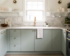 a kitchen with marble counter tops and white cabinets, along with open shelves on the wall