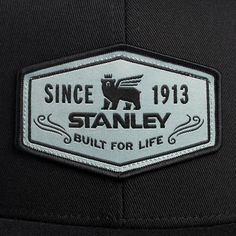 the back of a black hat with a white and silver patch that says, since 1911 stanley built for life