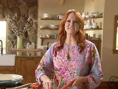 a woman standing in a kitchen cutting carrots