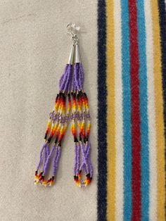 two pairs of beaded earrings sitting on top of a striped blanket next to each other