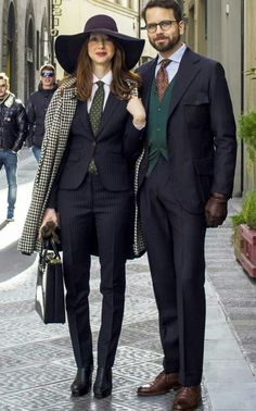 a man and woman dressed in business attire posing for the camera on a city street