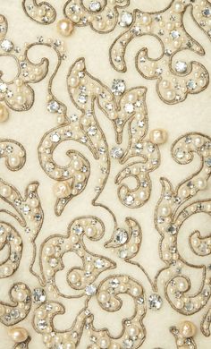 an embroidered fabric with pearls and crystals on it's side, showing the intricate design