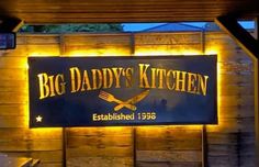 the sign for big daddy's kitchen is lit up with yellow lights on it