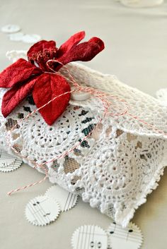 a white doily with red flower on top of it and some tags around the edge