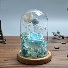 a glass dome with blue flowers inside on a wooden table next to cookies and other items