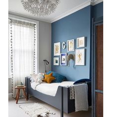 a bedroom with blue walls and pictures on the wall