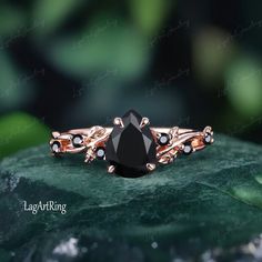 a black diamond ring sitting on top of a leafy green surface with leaves in the background