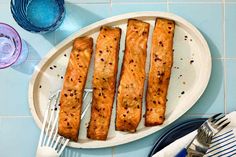 four pieces of fish on a plate with fork and knife