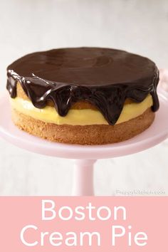 boston cream pie on a cake stand with the words boston cream pie in front of it