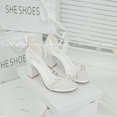 a pair of white high heeled shoes sitting on top of a box