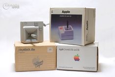 an apple computer sitting on top of a cardboard box next to another electronic device in its packaging