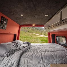 a bed in the back of a truck with a tv mounted to it's side