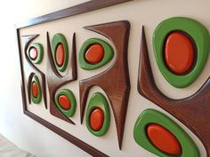 an abstract painting on the wall with red and green circles in between two brown frames