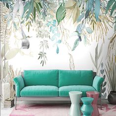 a green couch sitting in front of a white wall with plants on it and two vases next to it