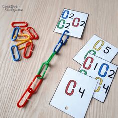 three pieces of paper with numbers on them sitting next to scissors and pegs that spell out the word c