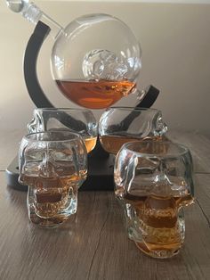 three glasses filled with liquid sitting on top of a wooden table next to a bowl