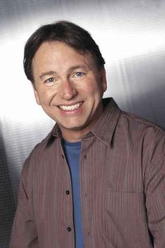 a man smiling in front of a metal wall