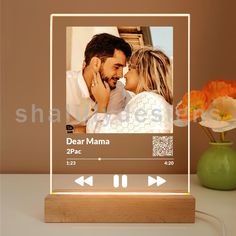 an illuminated photo frame with the words dear mamma on it next to a vase with flowers