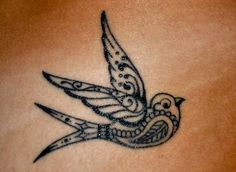 a tattoo on the back of a woman's stomach with a bird flying over it