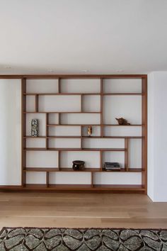 an empty room with a book shelf and rug on the floor in front of it