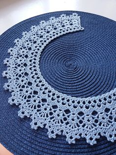 a crocheted doily on top of a blue mat