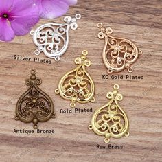 four different styles of filigree pendants on a wooden surface with flowers in the background