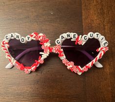 a pair of heart shaped sunglasses with candy canes on the sides and words can't be cute