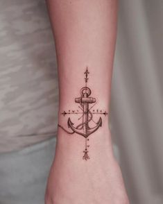 a small anchor tattoo on the wrist with compasses and stars around it's edges