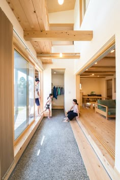 three people sitting on the floor in a room with wood paneling and open windows